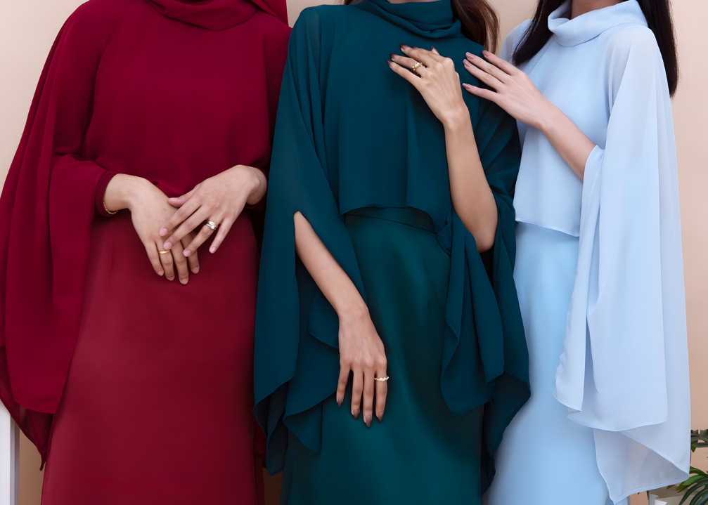 Three women in colorful traditional outfits standing together against a plain background